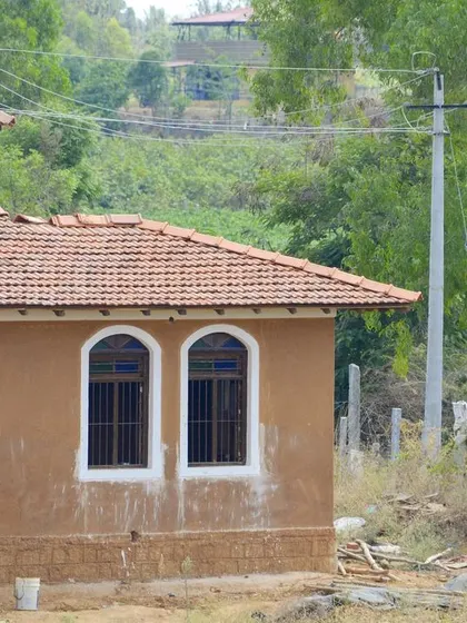 The exterior of the mud house, showing the combination of arched and rectangular windows. This variety in window design adds visual interest while ensuring ample natural light and ventilation.