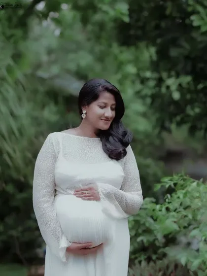 A gentle and introspective portrait. The soft focus on the background greenery makes the mother-to-be and her peaceful expression the center of attention.