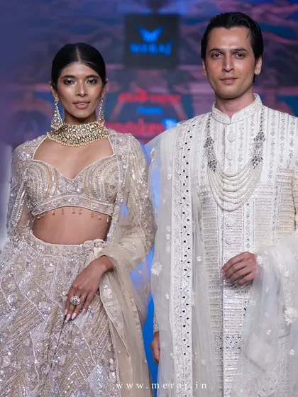 Unveiling elegance on the runway. This groom's gold sherwani is masterfully adorned with geometric accents, exuding sophistication and timeless charm alongside a dazzling gold geometric-designed bridal lehenga.