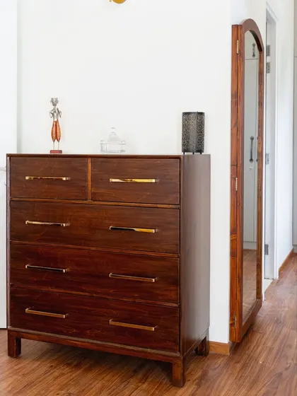 The chest of drawers placed in a hallway, serving as both a storage unit and a surface for decorative items.