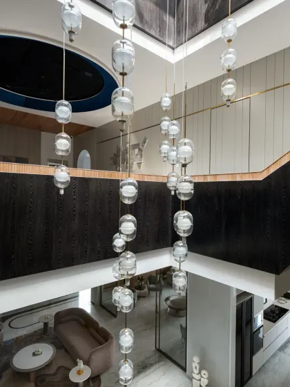 An exquisite triple-height chandelier is suspended within the atrium of The House of Dancing Screens. This custom sculpture was meticulously crafted to illuminate not just the dining area below, but the entire grand vertical space.