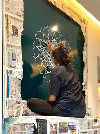 This is the raw reality of being a muralist. Sitting on a covered freezer, surrounded by newspaper, totally in the zone creating a mandala on a glass surface.
