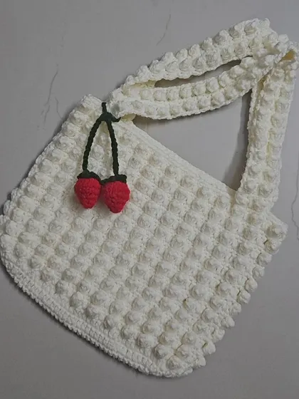 My Strawberry Popcorn tote bag, featuring a fun, bubbly texture from the popcorn stitch. I added a little cherry charm for a playful touch on this creamy white tote.
