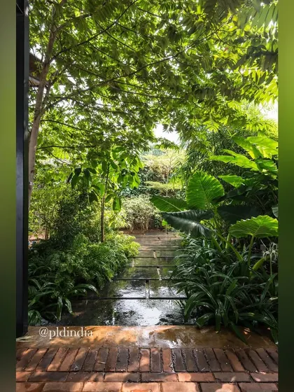A water channel runs through a brick patio, surrounded by lush greenery. The sound and sight of moving water adds a dynamic and soothing element to this intimate garden space.