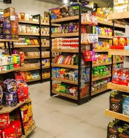 A view of the corner displays and shelving units, stocked with a variety of packaged goods. The design uses a mix of wood and metal for a modern yet warm feel.