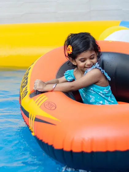 This little adventurer is having a blast in her inflatable boat, ready to explore the pool.