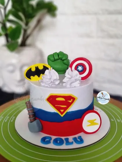 Avengers assemble! This superhero themed cake brings together iconic symbols like the shields of Superman and Captain America, Batman's logo, and Hulk's fist for an action-packed birthday.