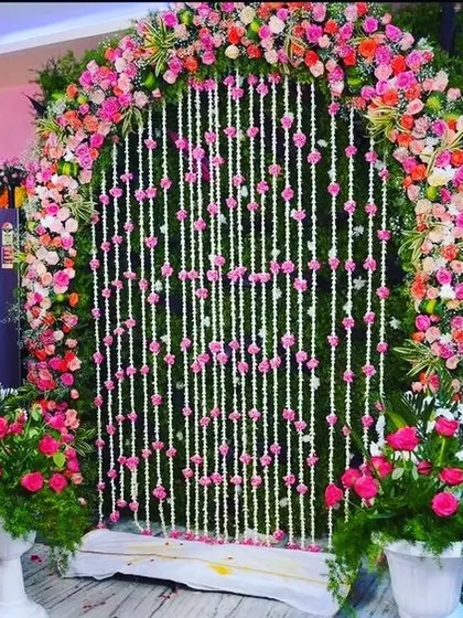 A beautiful indoor setup for a traditional ceremony, with a floral arch and hanging flower strings.