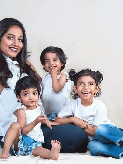 A joyful family portrait of a mother and her three children. Their bright smiles and casual poses create a feeling of warmth and happiness.