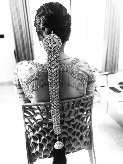 A black and white shot highlighting the incredible texture and detail of a bridal 'Jadai'. This shows the intricate metalwork of the hair jewellery against the tightly woven braid.