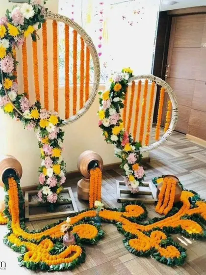 An artistic and modern take on traditional decor. This setup features marigold flowers pouring out of brass pots, combined with circular frames for a contemporary floral installation.