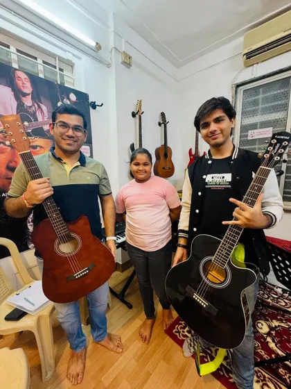 Two of our adult guitar students and a young peer pose with their instruments. This photo perfectly illustrates the all-ages community we have built at The Music Gurukul.