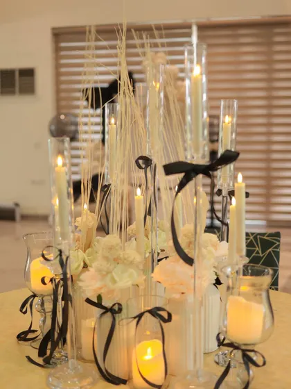A beautiful centerpiece for the bow-themed party. We used a collection of tall glass candle holders, white flowers, and delicate black ribbons to create an elegant and romantic focal point.