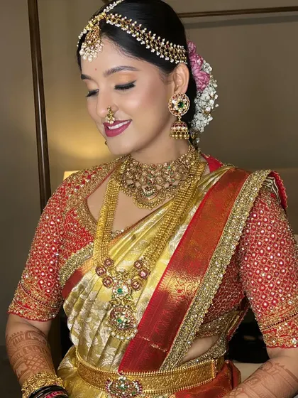 A beautiful close-up of the bride's makeup. The eyes are softly defined, and the lip color is a stunning shade of berry, perfectly complementing her red and gold saree.