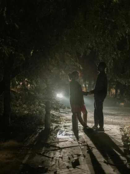 A silhouette of a couple holding hands against the headlights of a car, creating a moody and cinematic feel.