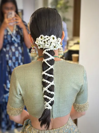 A beautiful bridal braid for a destination wedding in Udaipur, adorned with a string of pearls and a cluster of fresh daisies.