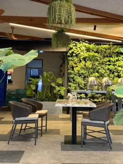 A seating nook in the café, framed by lush planters. The design creates intimate spaces within a larger open area, encouraging slow moments and social ease.