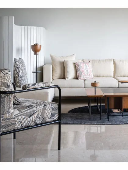 Another view of the 'Powai House' living room, showcasing a custom-designed armchair with a unique patterned fabric. The piece adds a graphic element to the otherwise serene space, proving that even in minimalism, there is room for bold expression.