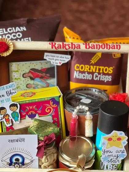 A close-up of the personalized elements in the sibling Rakhi hamper, including photos and stickers.