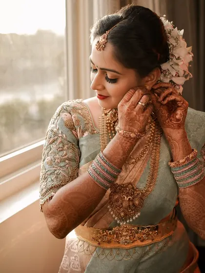 A close-up of a bride putting on her traditional jewelry, a candid moment filled with anticipation.
