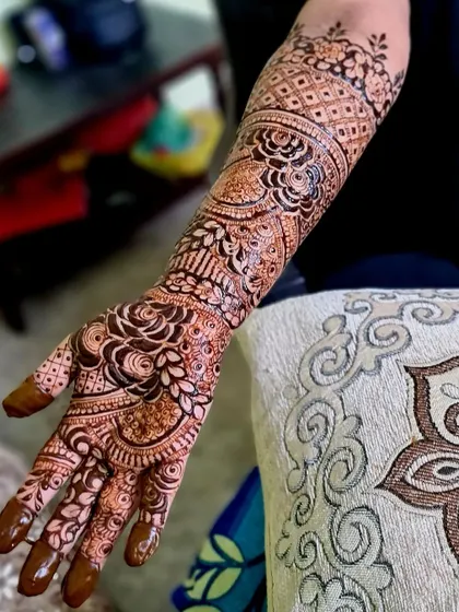 This bridal design showcases bold rose patterns on the palm and forearm, connected by intricate vine and checkerboard fillers.