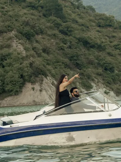 A beautiful wide shot of the couple on the speedboat, with the bride-to-be pointing towards the horizon, symbolizing their journey ahead.