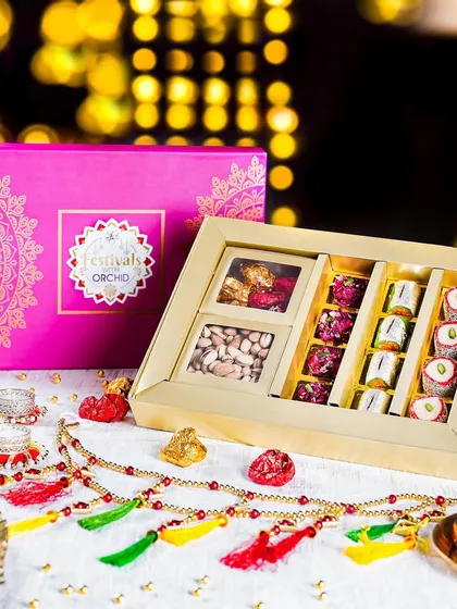 A premium Diwali hamper with a mix of dry fruits and sweets, styled with a traditional toran. The bright, festive colors and elegant packaging make it a perfect gift.
