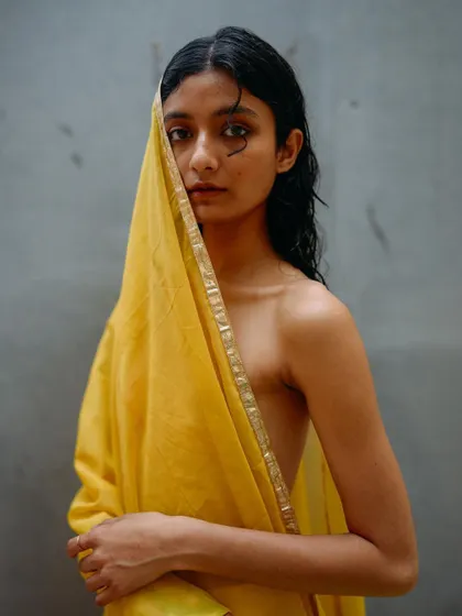 A portrait from the yellow drape series where the fabric veils part of the model's face. The direct gaze through the fabric creates a compelling and intimate connection.