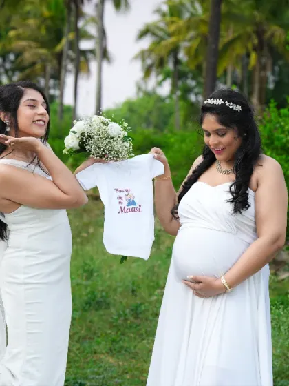 A sweet moment between friends, holding up a "Tia in the making" onesie. A perfect way to celebrate the aunt-to-be.