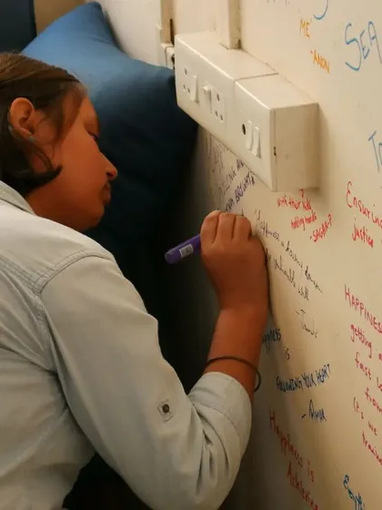 A close-up of a volunteer writing on the wall, a symbol of our collective spirit.