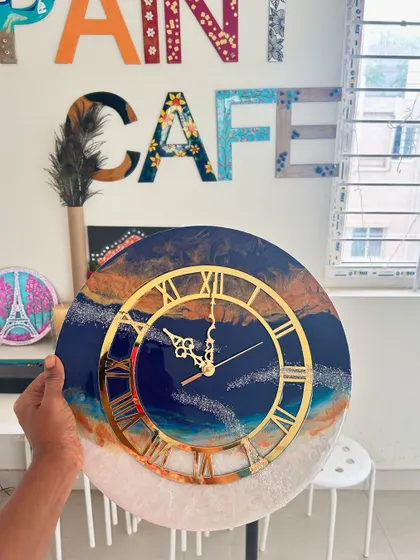 A resin clock depicting a beautiful sunset over the ocean, with warm oranges blending into a deep blue.