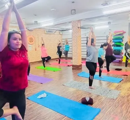 Our instructor guiding the class through a balancing posture. We provide hands-on guidance to help everyone, especially beginners, feel confident.