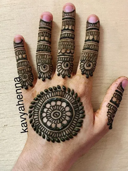 A classic mandala, or gol tikki, design on the palm. This minimalist style is complemented by detailed patterns on each finger, making it a popular choice for parties and festivals.