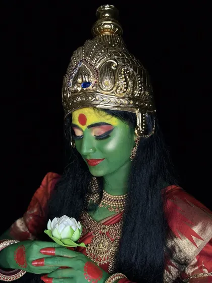 Another pose from the goddess-themed shoot, showing the character holding a lotus flower. The makeup remains flawless and expressive from every angle.