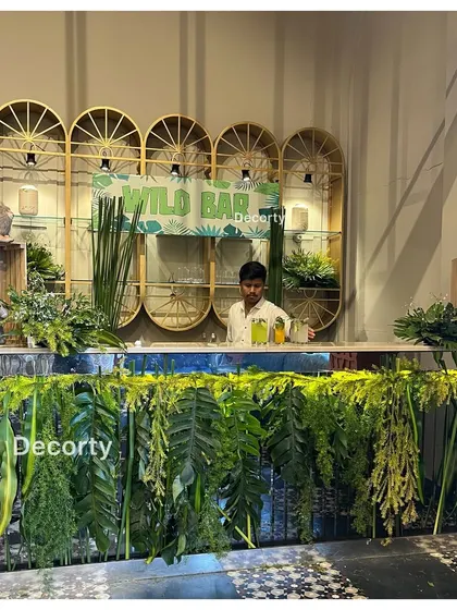 A 'Wild Bar' setup for a jungle safari party, complete with lush greenery and themed shelving.