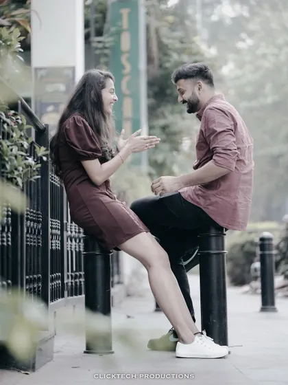 A candid shot of a couple having a lively conversation while sitting on city bollards, capturing their natural interaction.