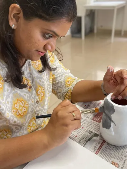 A close-up of the penguin planter painting in progress, showing the focus and detail involved.