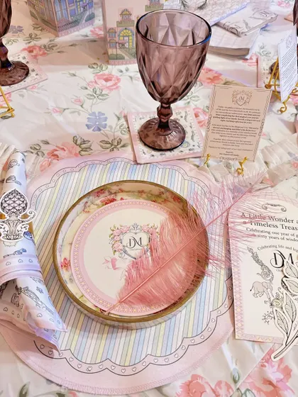A close-up of the exquisite table setting, featuring custom monogrammed plates, striped placemats, and a delicate pink feather.