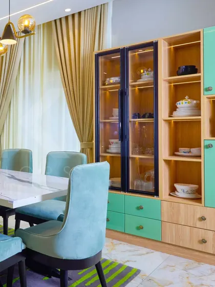 A closer look at the crockery unit in the green-themed dining room, featuring a mix of glass-front and closed cabinets.