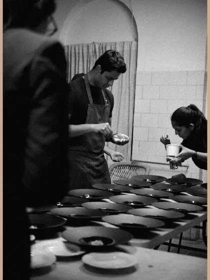 A black and white shot of my team plating dishes for the saree exhibition dinner, showing the focus and precision required.
