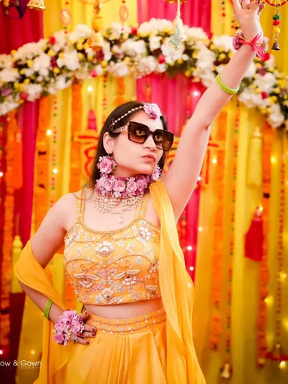 The bride shows off her fun side with a cool pose and sunglasses at her Haldi. It's a perfect blend of tradition and modern style.