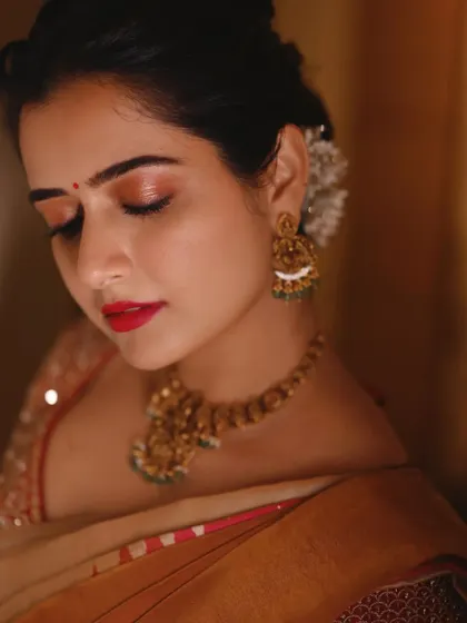 A close-up portrait of actress Ashika Ranganath, focusing on the emotion in her eyes. The warm lighting and traditional attire create a look of timeless elegance for her portfolio.