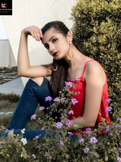 An outdoor portrait where the model is seated amongst purple flowers. The natural elements frame her beautifully, creating a soft and romantic image.