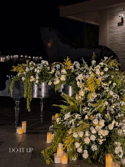 A grand piano, overflowing with white and yellow florals and surrounded by candles, created a romantic and artistic focal point for this elegant sangeet in Udaipur.