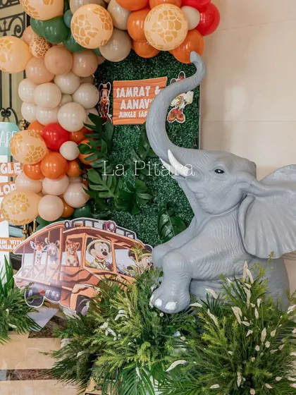 A detailed decor piece featuring an elephant statue, a safari bus cutout, and a vibrant balloon arrangement.