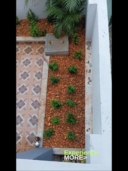 An overhead view of a pebble garden next to a tiled patio. This design is perfect for adding greenery to small, paved areas.