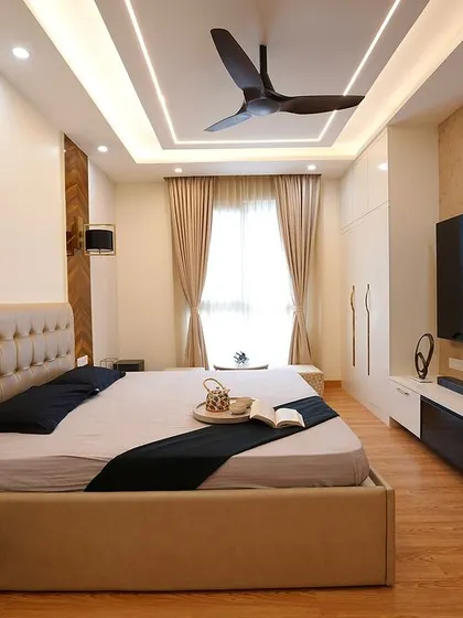 A contemporary bedroom featuring a tufted beige headboard, a stylish TV unit, and dramatic chevron-patterned wood paneling on the wall for a touch of modern luxury.