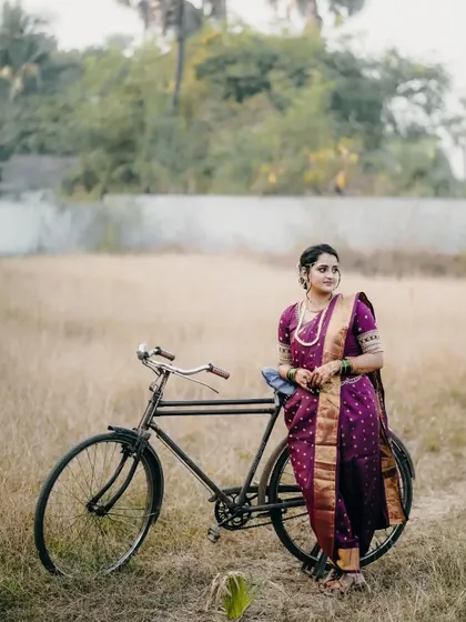 A unique, retro-style portrait of the bride with a vintage bicycle in a rustic setting.