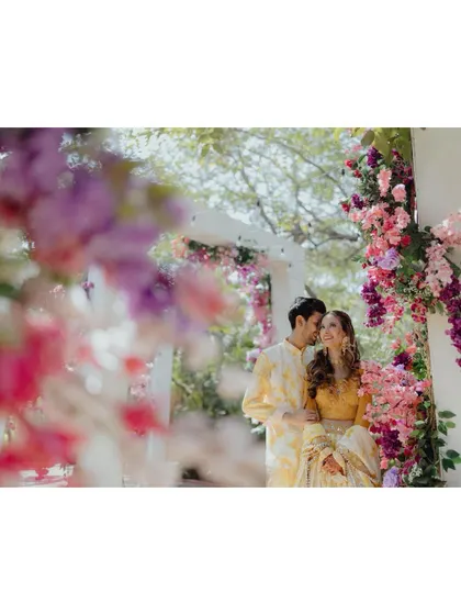 A romantic portrait of the couple at their Mehendi, framed by beautiful pink and purple bougainvillea, creating a soft and dreamy effect.