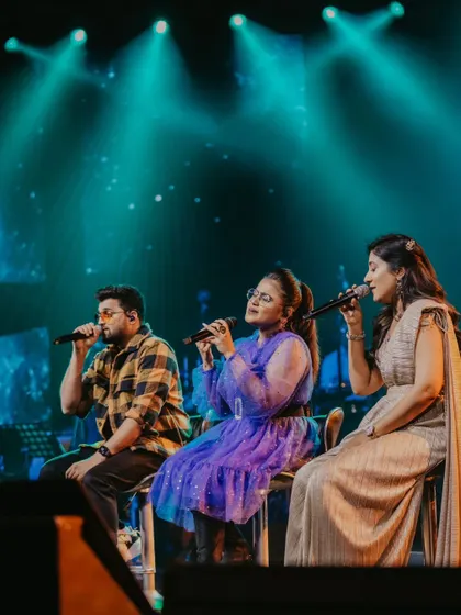 A trio of talented singers performing on stage at the A.R. Rahman concert. The lighting and their focused expressions showcase the magic of a live music event.